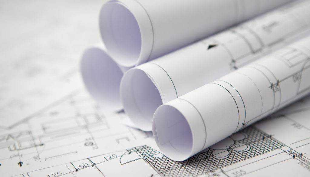 Blue prints on a table with rolled blueprints