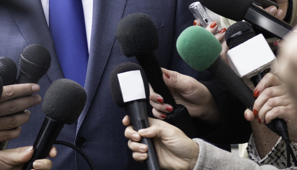 A man in a suit being interviewed by the media