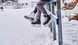 Couple wearing ice skates sitting on a guardrail