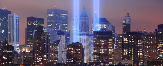 New York City Manhattan downtown skyline at night from Liberty Park with light beams in memory of September 11 viewed from New Jersey waterfront.