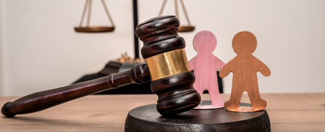 Judge's gavel, scales of justice, and two wooden figures symbolizing children, family law, guardianship and protection of rights in civil court, legal inheritance
